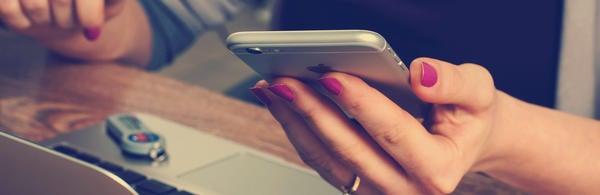 hand holding a cellphone over a laptop (c) William Iven 8515 unsplash